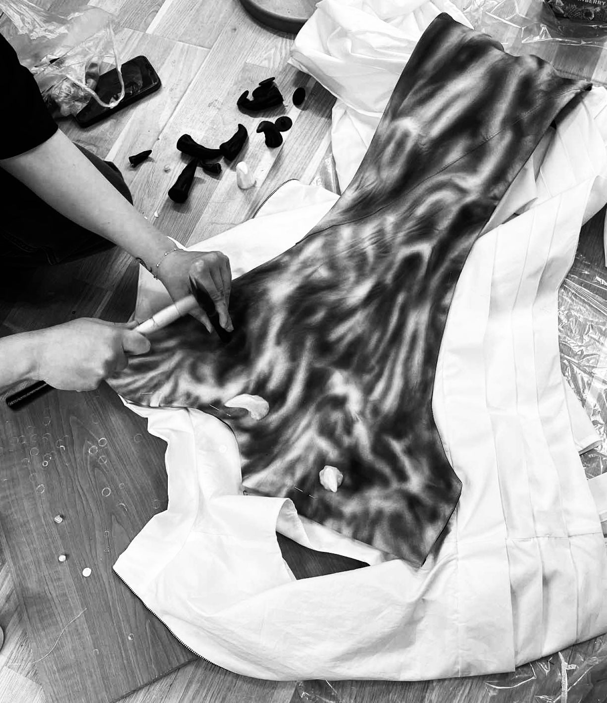 Person working on a leather project with tools on a wooden floor.